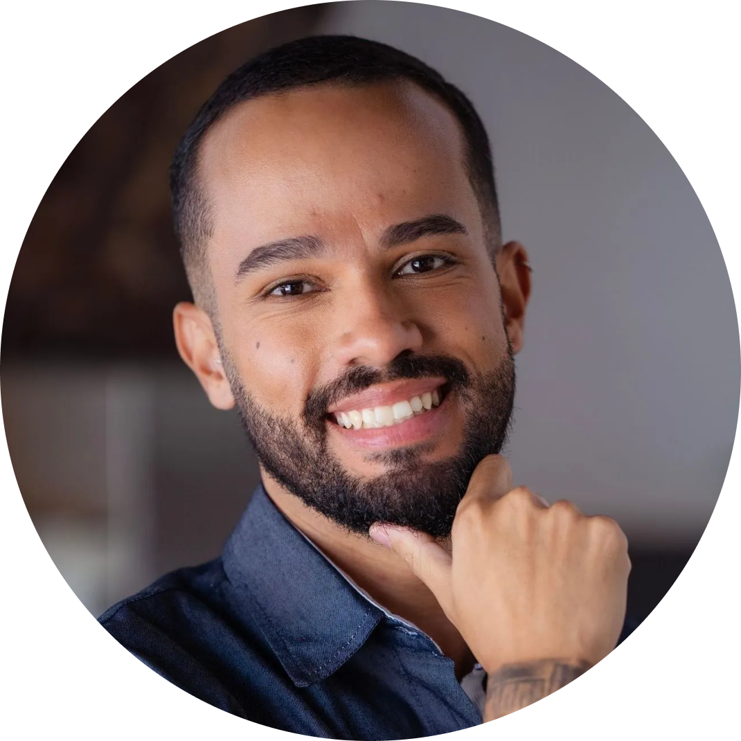 Um homem com barba está sorrindo em círculo com a mão no queixo.