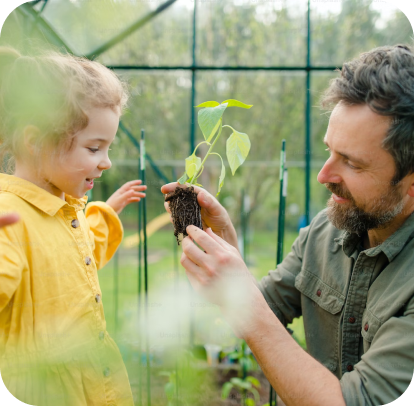 Um homem e uma menina estão olhando para uma planta em uma estufa.