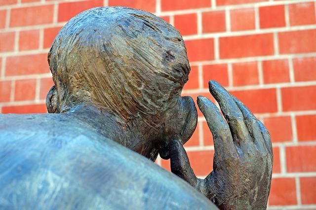 Estátua de um homem tentando escutar para ilustrar a gestão de riscos sociais