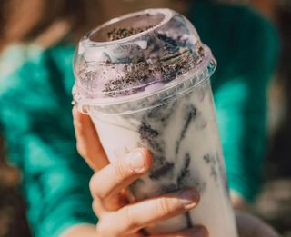 A woman is holding a cup of milkshake in her hands.