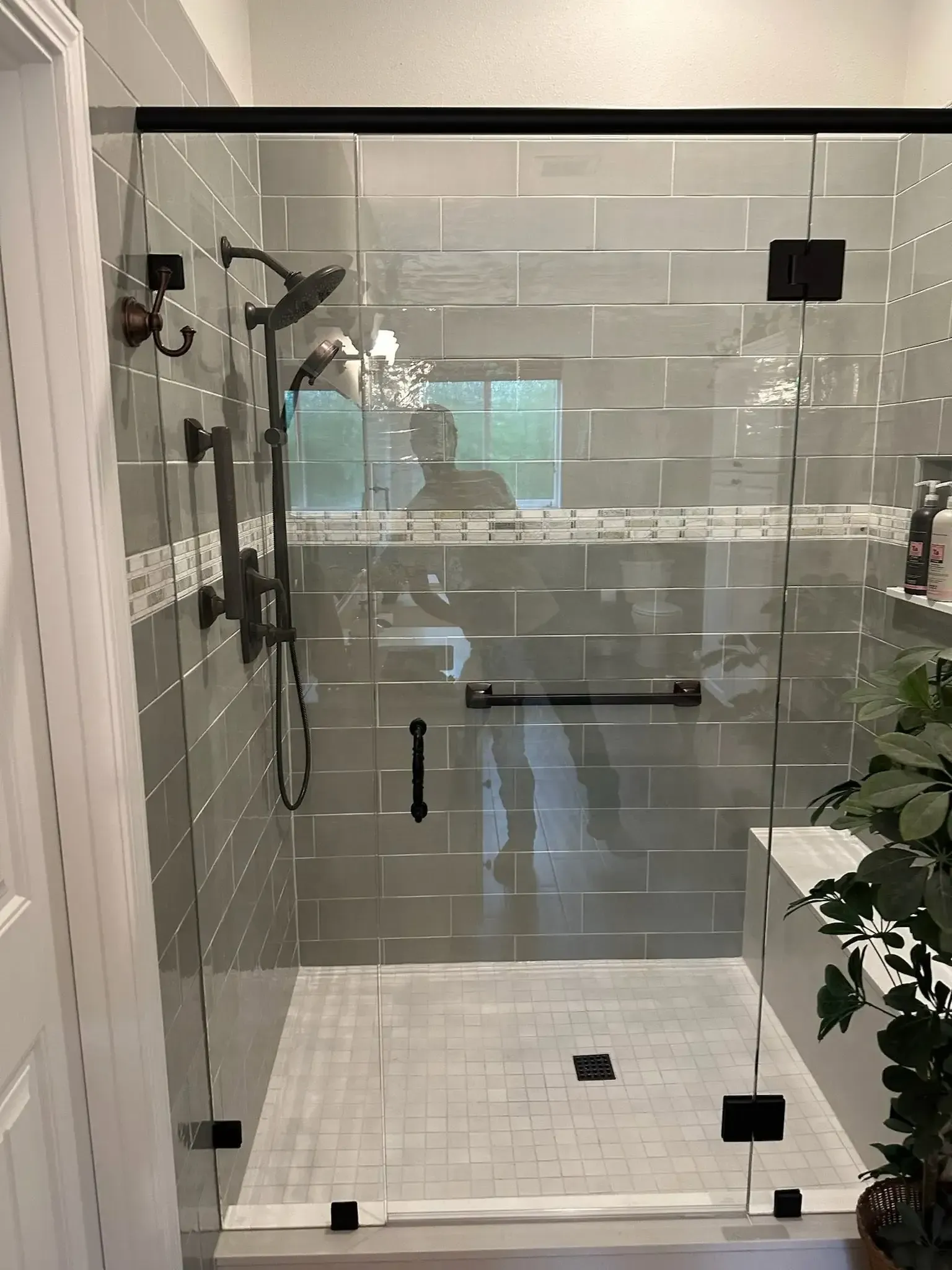 Glass shower enclosure with white subway tile and a white tiled bench in a bathroom