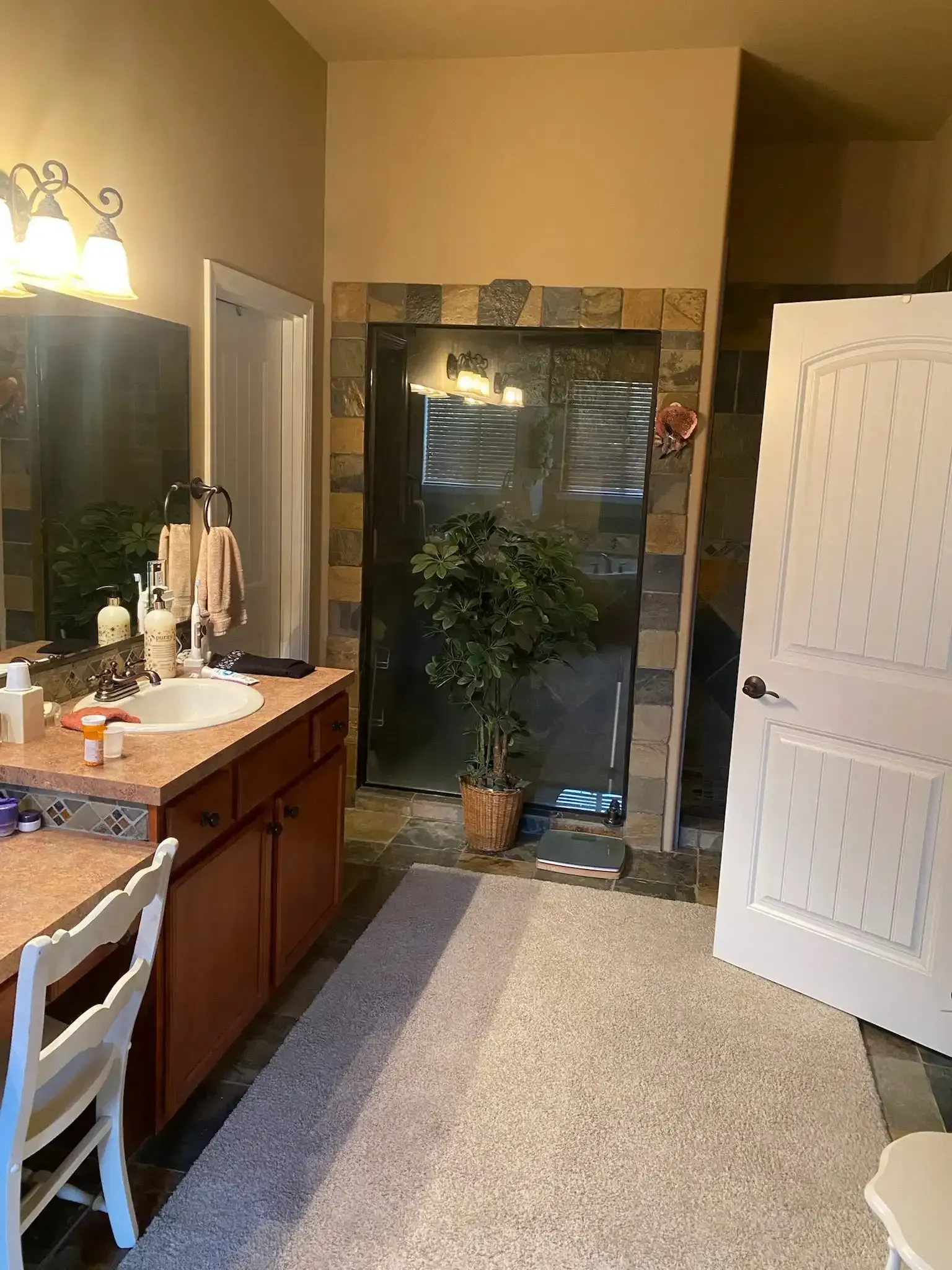 Bathroom with vanity and mirror on the left, open door, and glass shower area at the back.