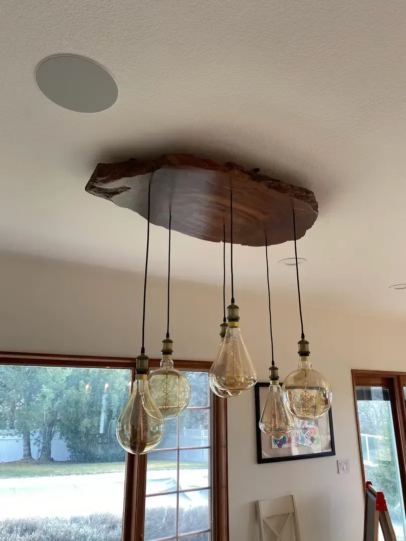Hanging pendant lights and a woven light fixture mounted on a ceiling in a bright room