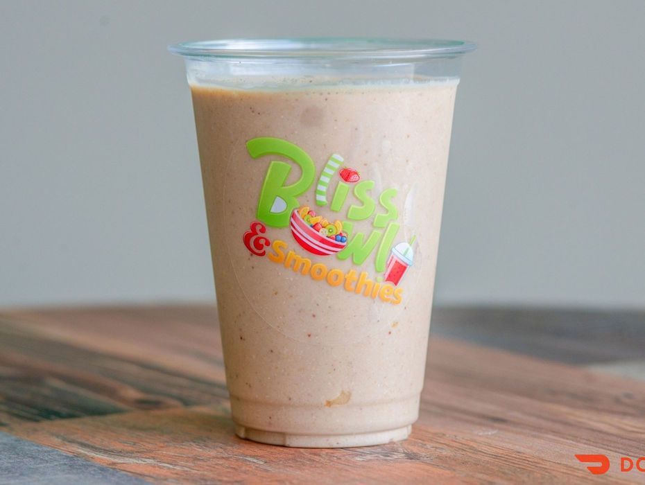 A clear plastic cup of iced latte with colorful logo on a wooden table