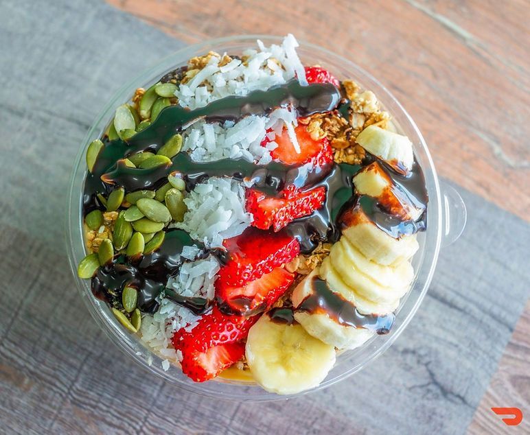 Colorful smoothie bowl topped with strawberries, banana, kiwi, pistachios, and chia seeds