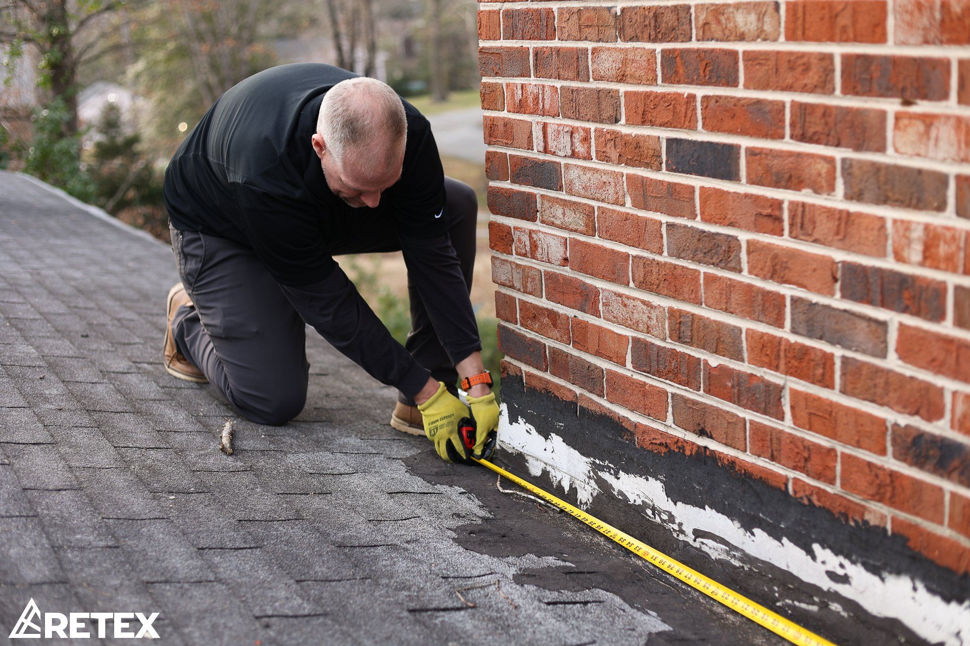 Image of RETEX's Mark Erickson measuring chimney base length for flashing replacement. 