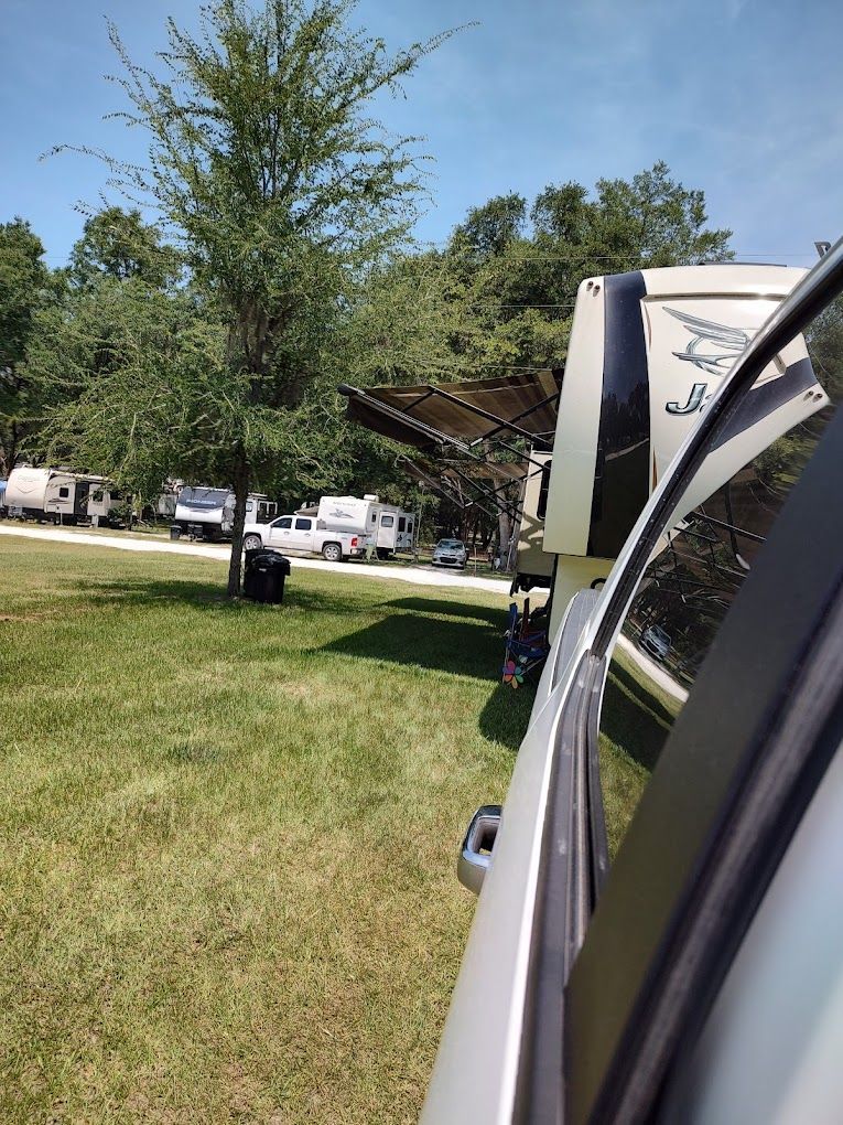 A car is parked in a grassy field next to a rv.