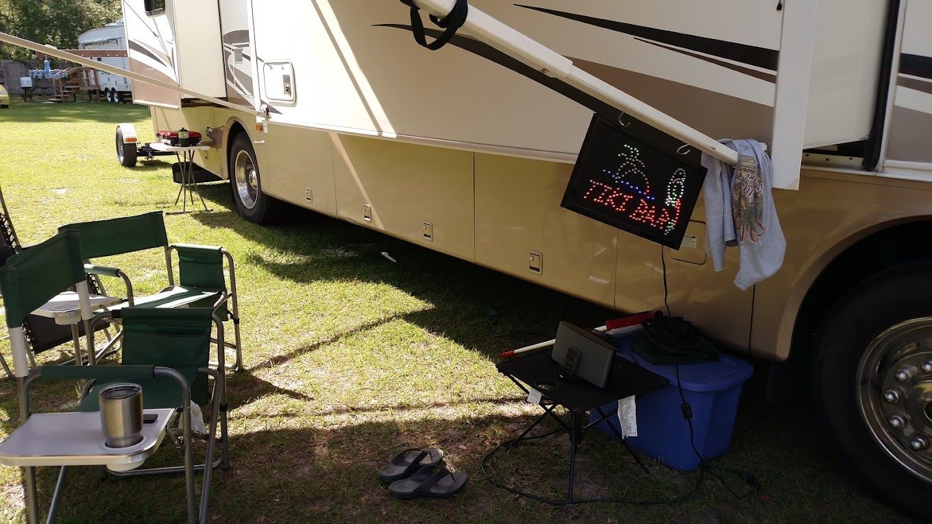 A rv is parked in a grassy area with chairs and a table