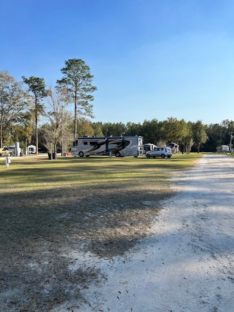 A rv parked in a grassy field next to a dirt road.