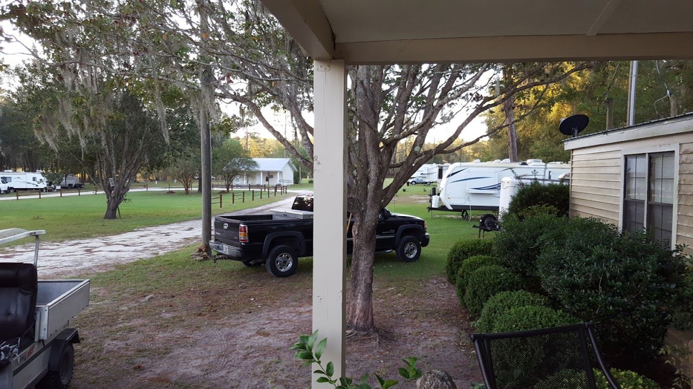 A truck is parked under a covered porch in front of a mobile home.
