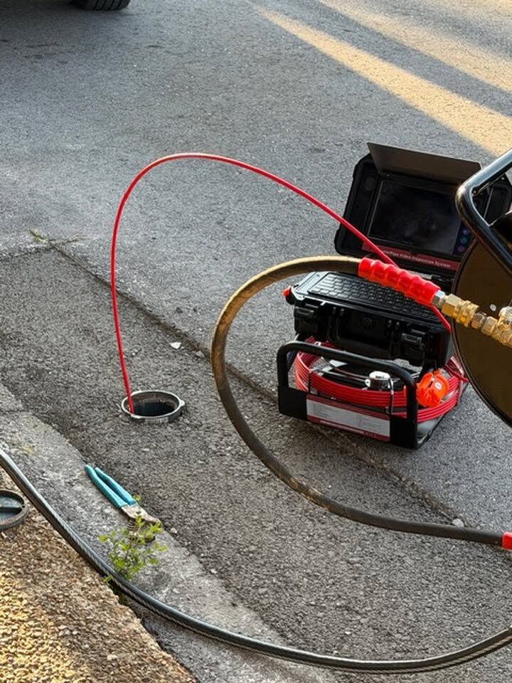 Roadside jump starter connected to a vehicle battery with red and black cables near the pavement