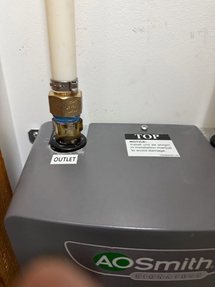 AO Smith water heater with white pipe and brass fitting on top in a utility area