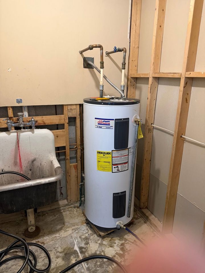 White water heater in unfinished basement beside exposed studs and a utility sink.