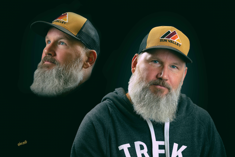 Ben VanSlander Shop Owner-Man with gray beard wearing a hat/hoodie, posing with black backdrop, with a side shot of his head.