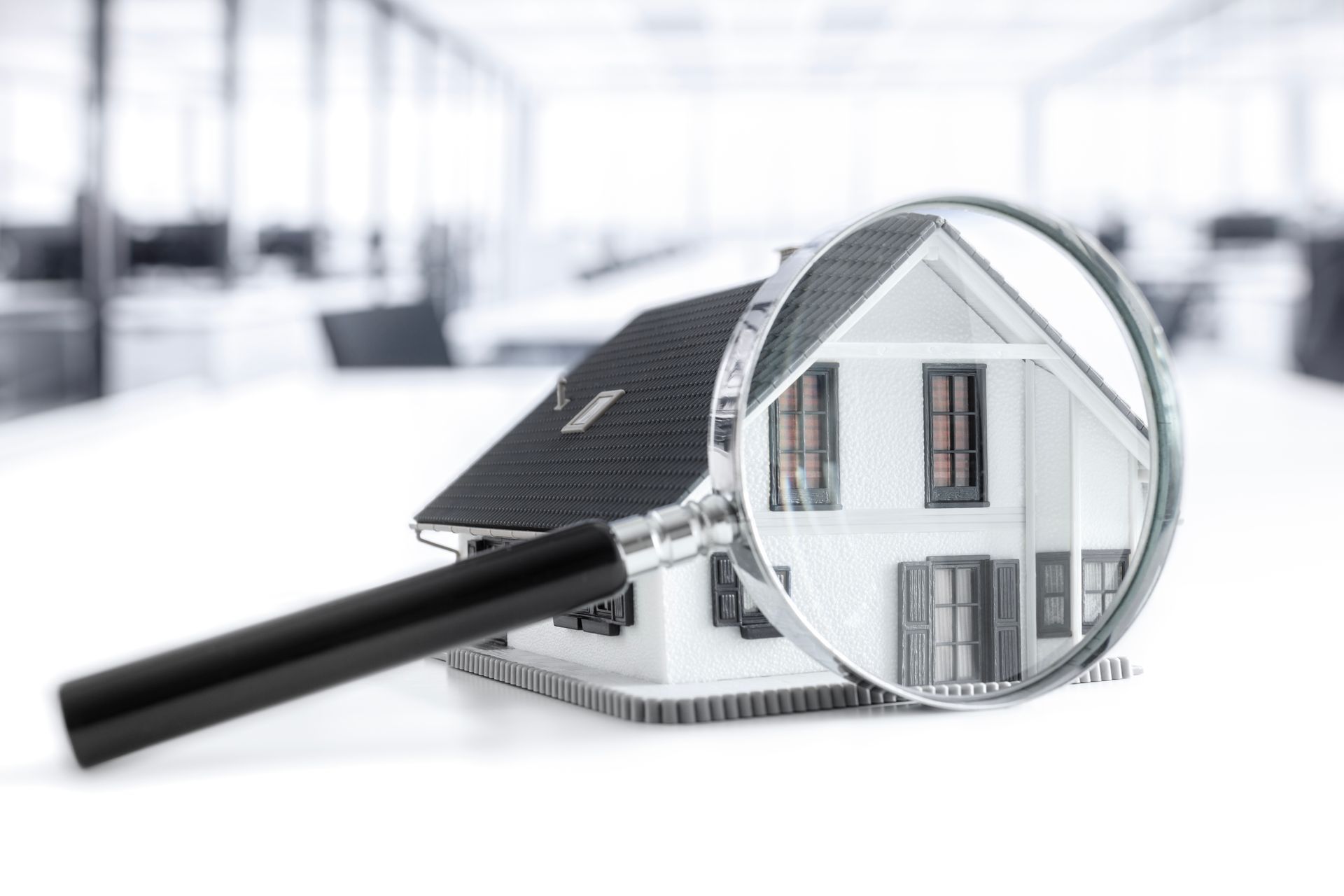 Magnifying glass over a model house, highlighting home inspection or real estate inspection concept