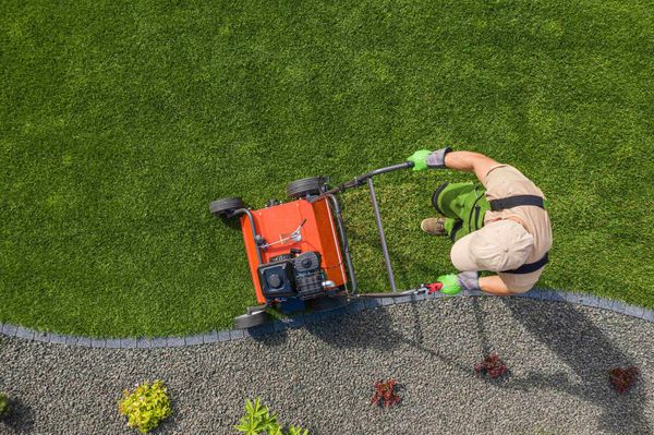 an aerial view of a man using a lawn mower on a lush green lawn