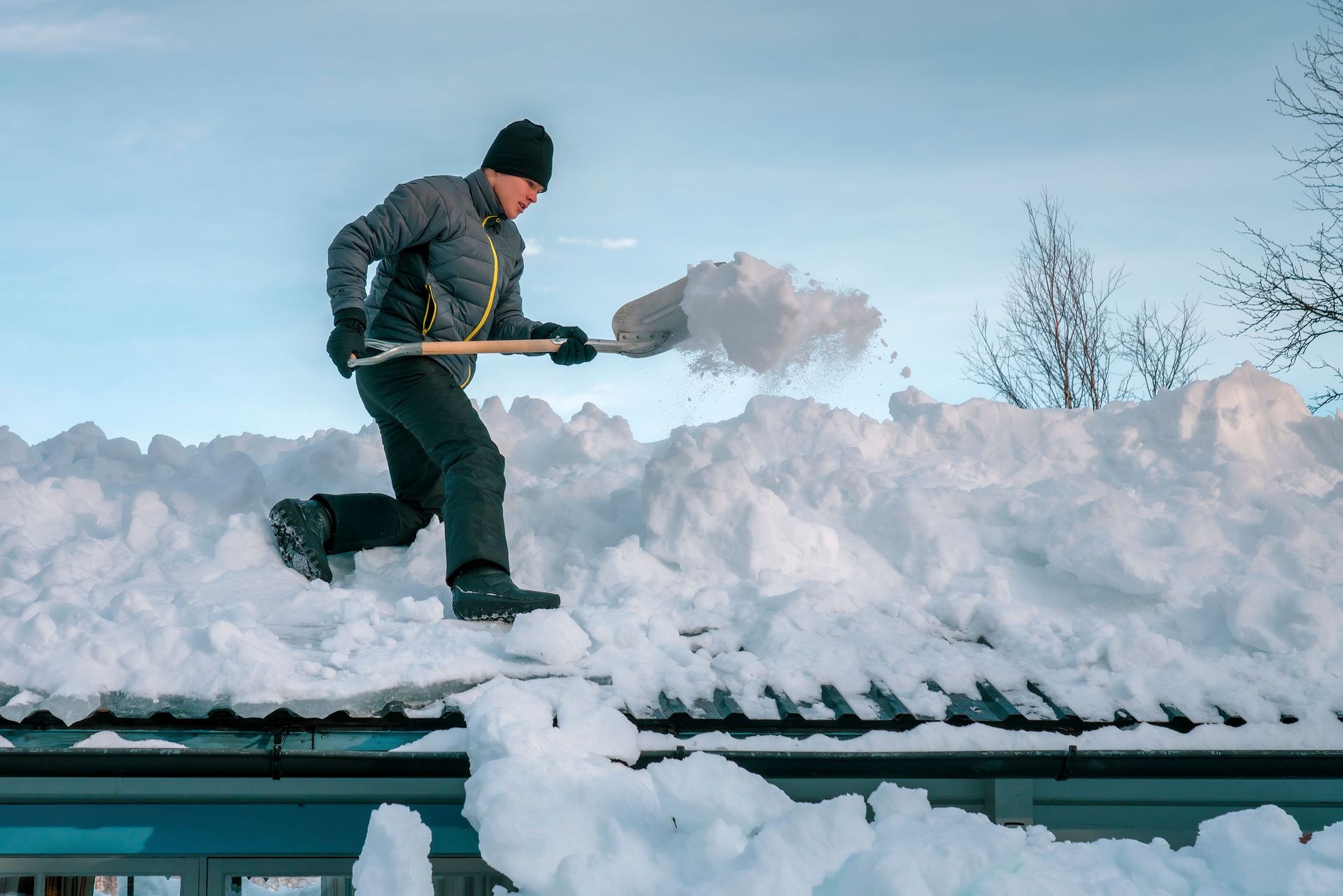 a man is shoveling snow off of a roof with a shovel