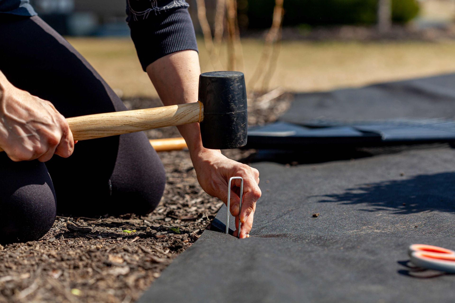 a person is using a hammer to hammer a nail into the ground