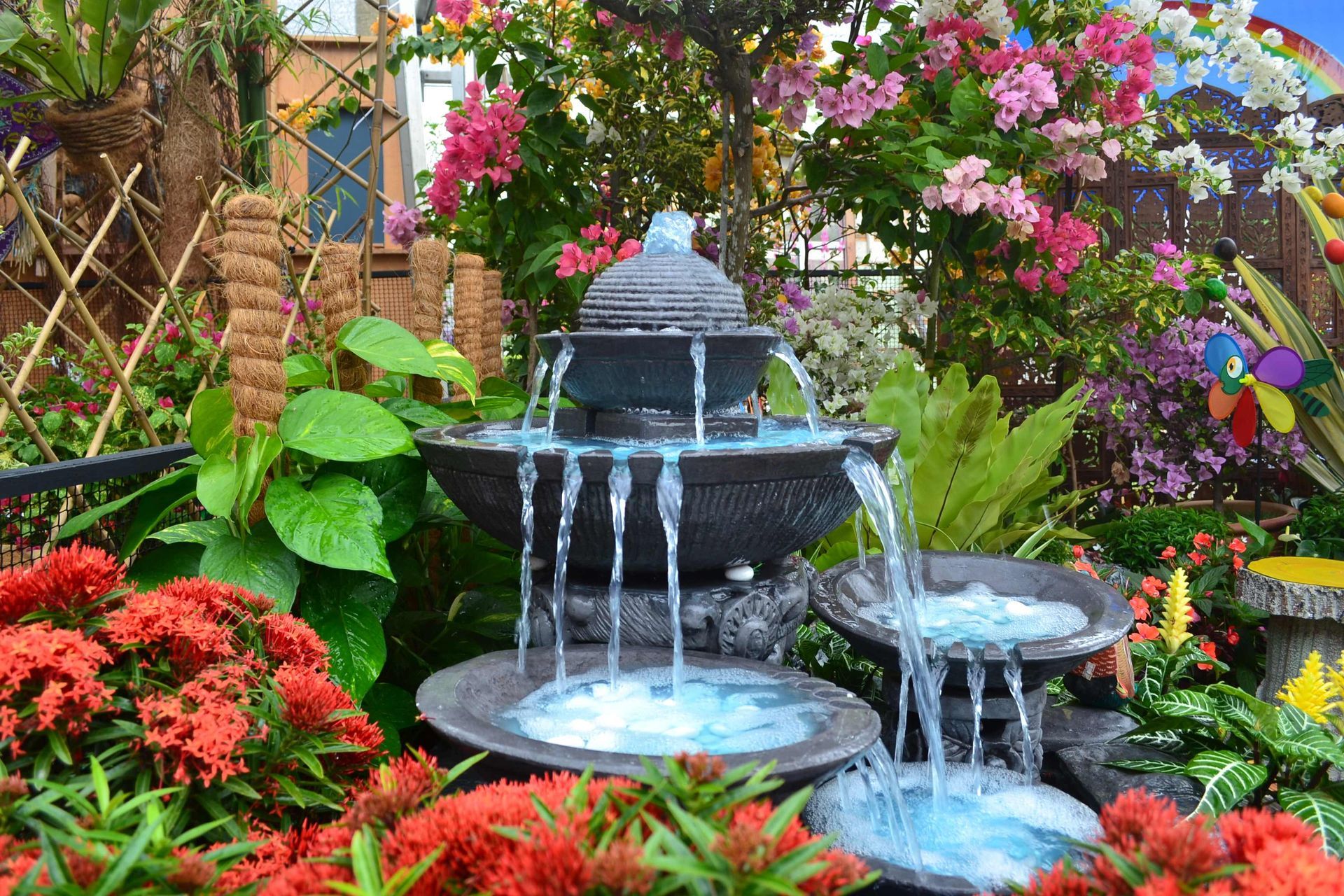 a fountain in a garden surrounded by flowers and plants