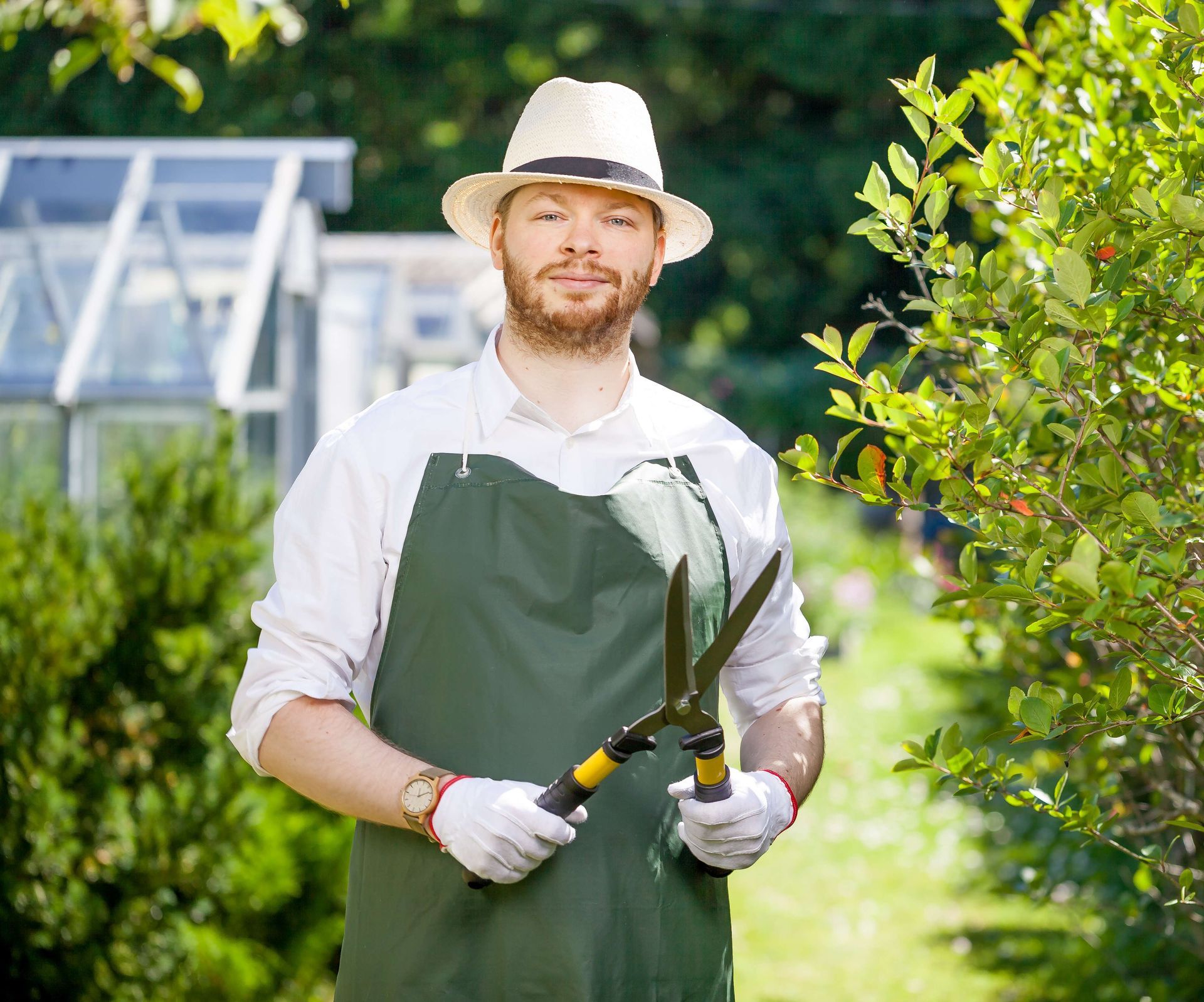 a man in a hat and apron is holding a pair of scissors