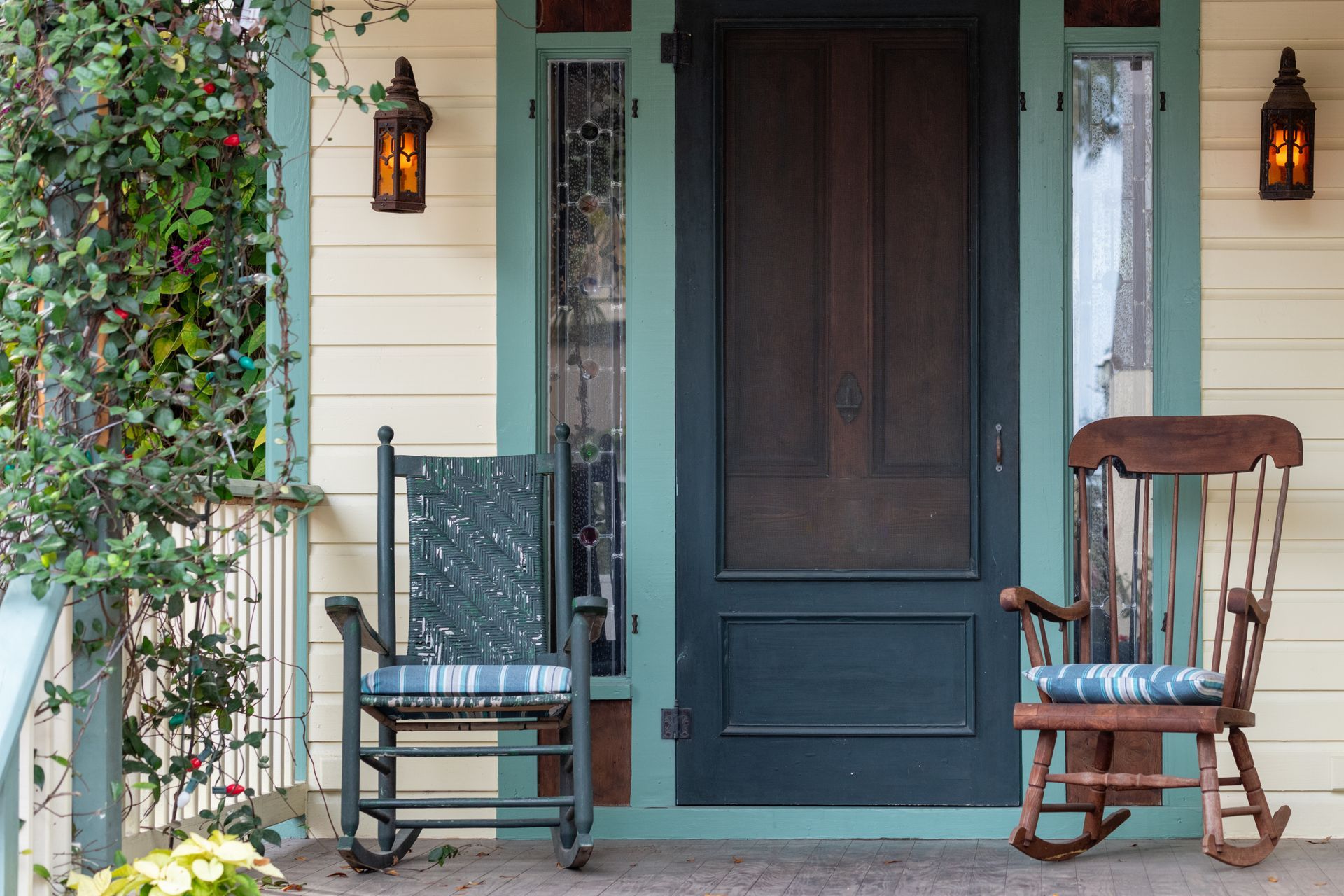 Two rocking chairs on a front porch. A door with a screen is closed behind them.