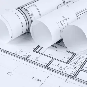 Architectural blueprints, rolled and unfolded, with detailed floor plans and measurements.