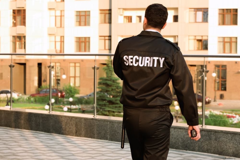 A security guard is walking in front of a building.
