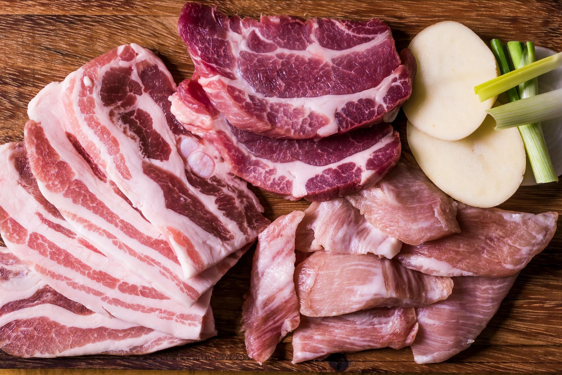 A wooden cutting board topped with sliced meat and potatoes.