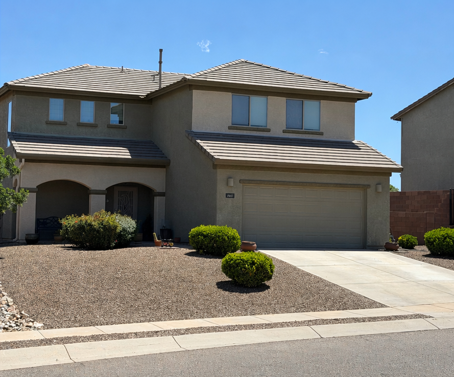 Two-story beige stucco suburban house with a two-car garage and desert landscaping
