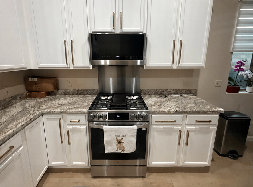 Modern kitchen with white cabinets, granite counters, stainless steel stove, and black range hood