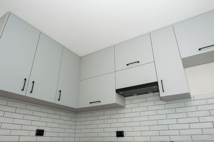 Modern gray kitchen cabinets above a white subway tile backsplash, viewed from below
