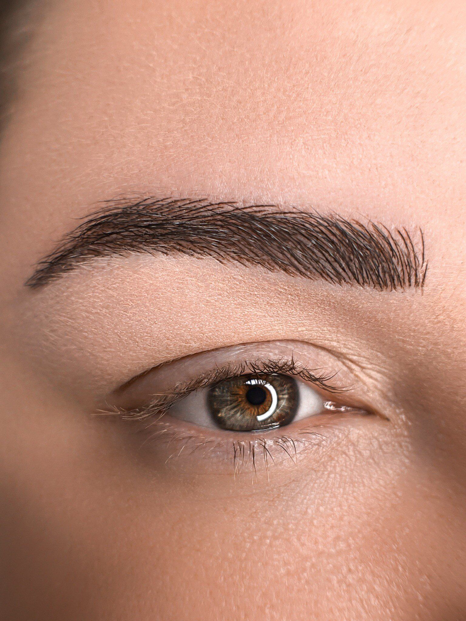 Nahaufnahme einer gepflegten Augenbraue und eines braunen Auges mit natürlichem Make-up.