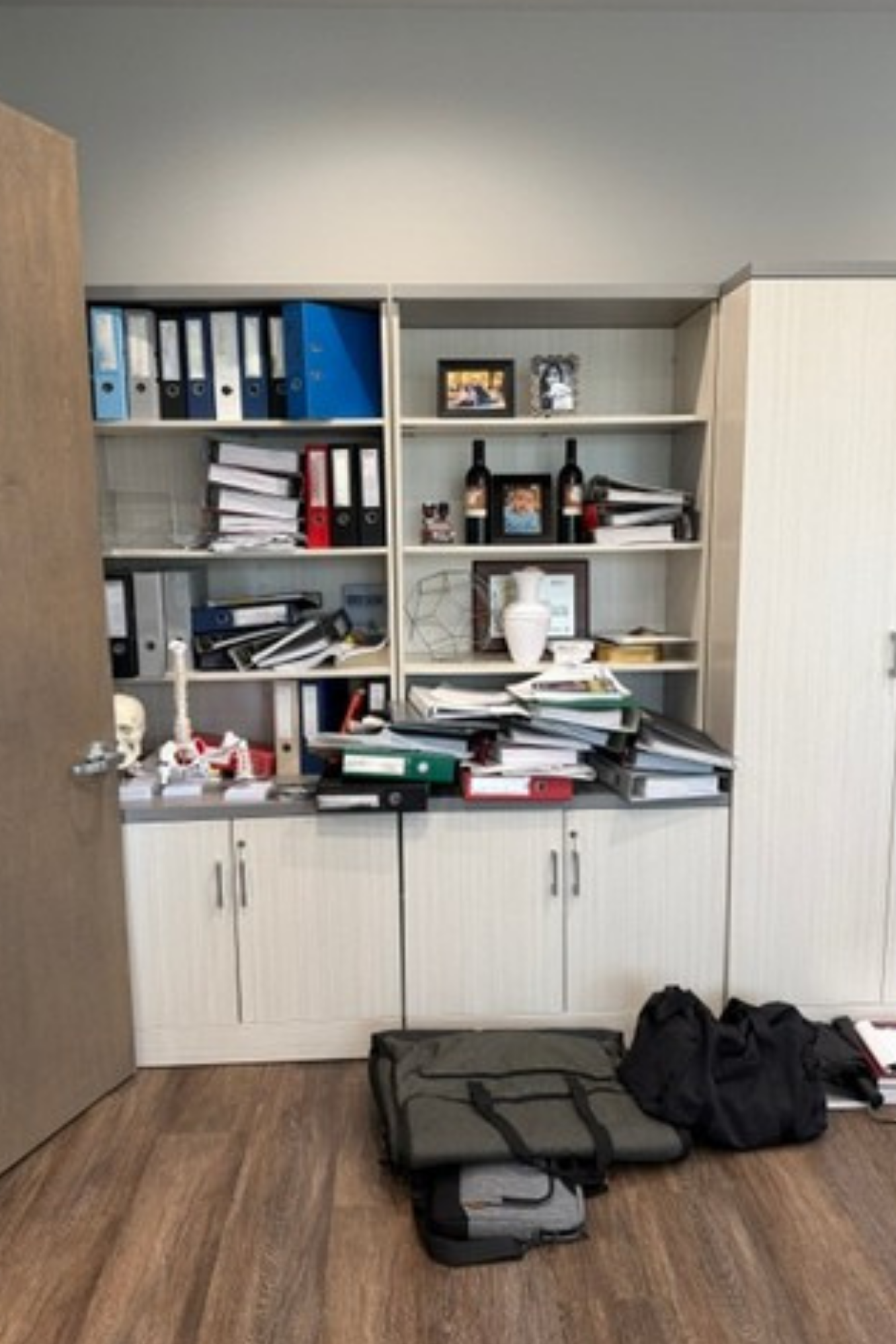 Office storage cabinet with binders, papers, and bags on the floor