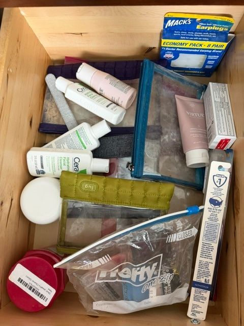 Assorted toiletries and small medicine boxes in a wooden drawer organizer.
