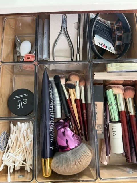 Makeup brushes and cosmetics organized in clear compartment trays.