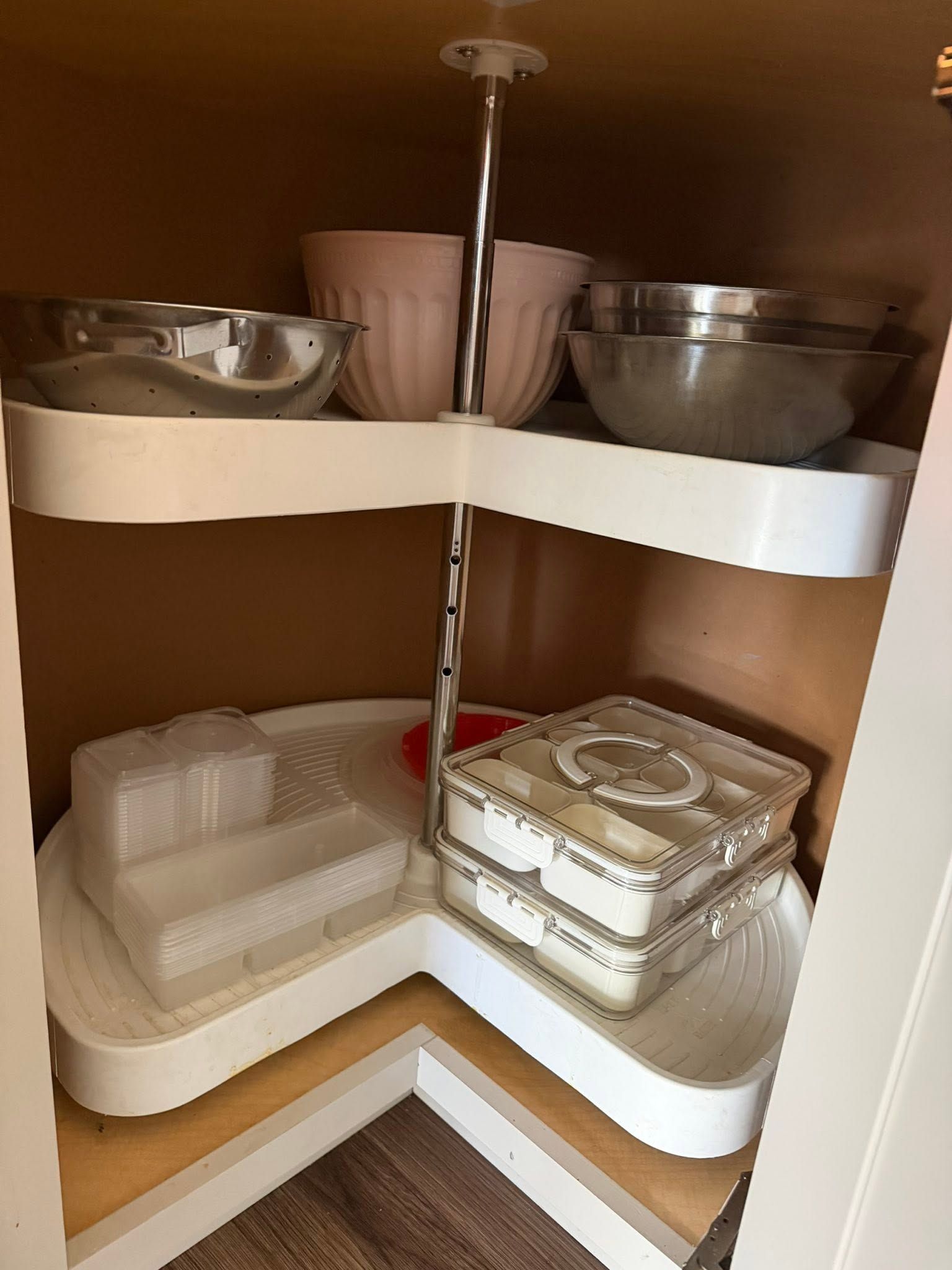 Under-sink cabinet with rotating shelves holding bowls, containers, and kitchen storage items