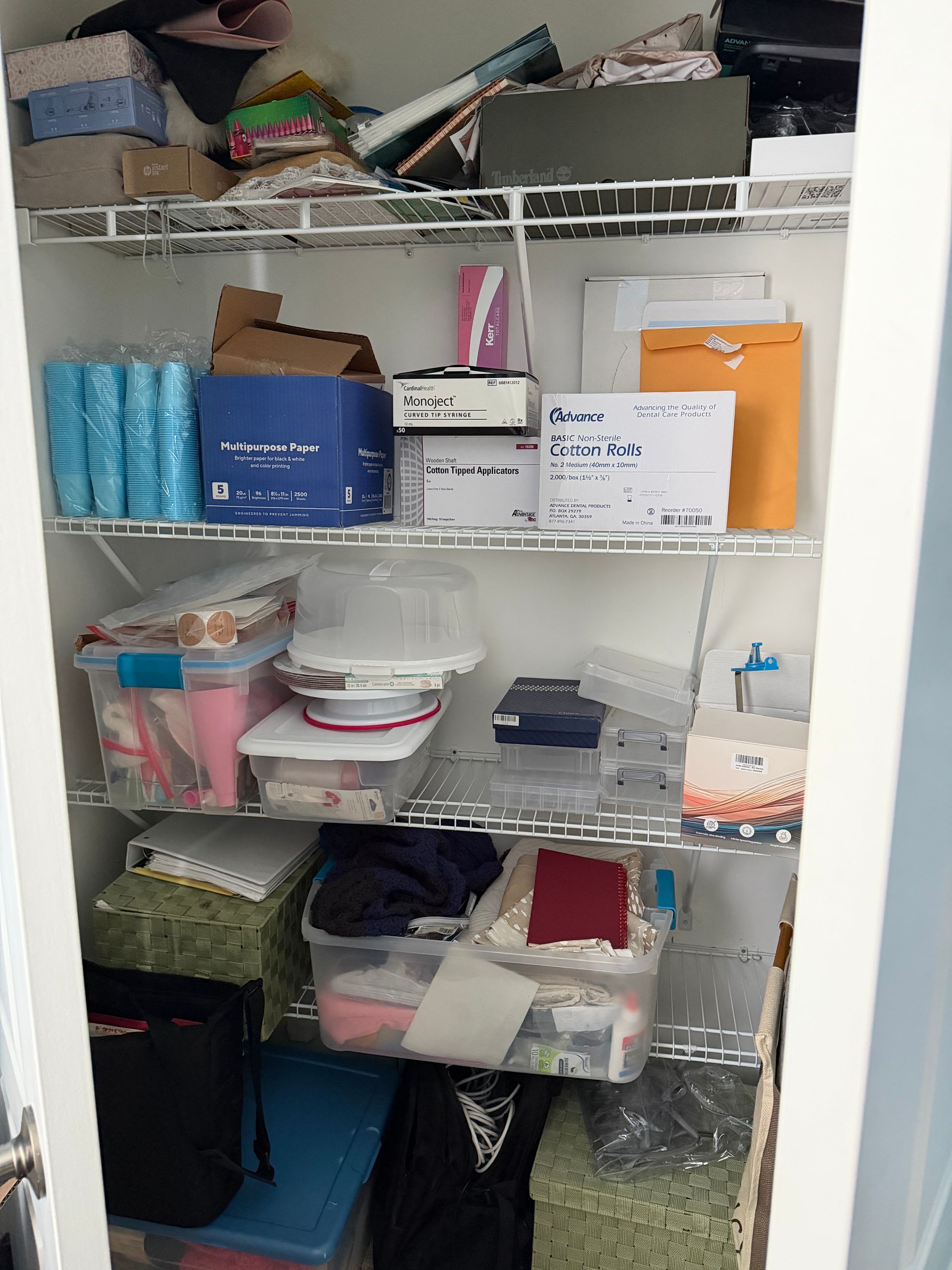Wire shelving in a storage room packed with bins, boxes, folded linens, and household supplies.