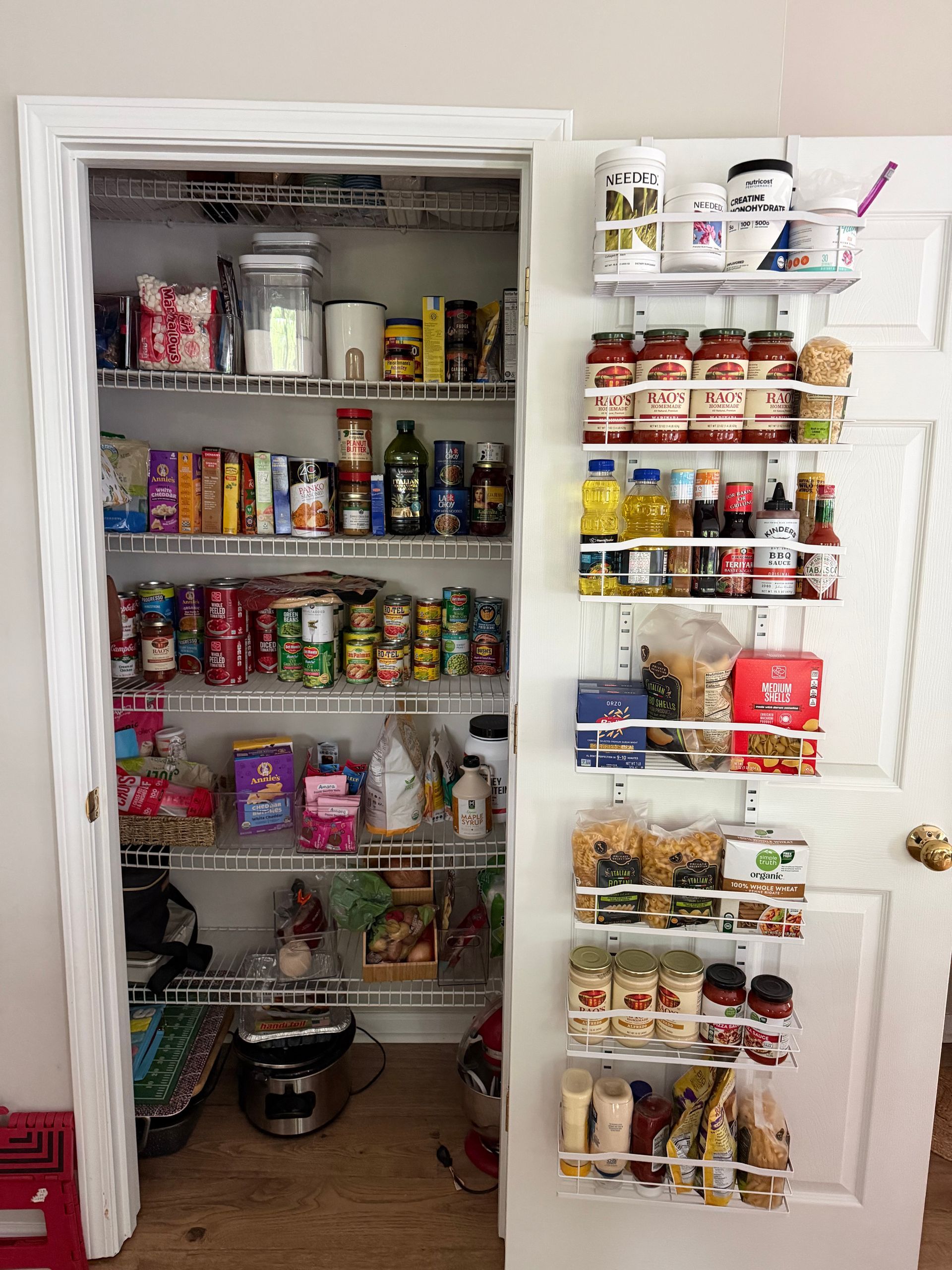 Open pantry and hanging door organizer filled with snacks, canned goods, and condiments.