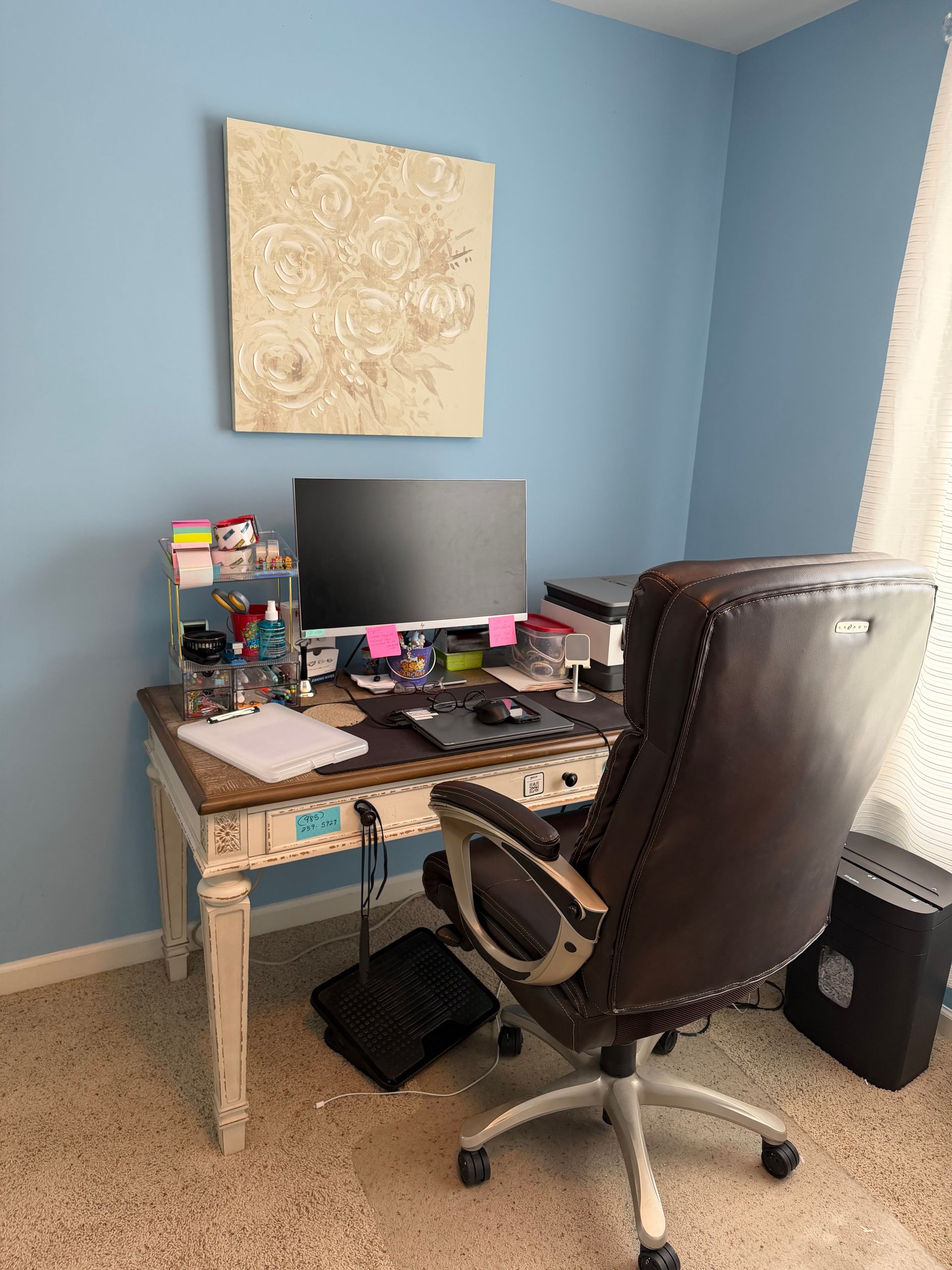 Small home office with a desk, computer monitor, keyboard, chair, and blue walls.