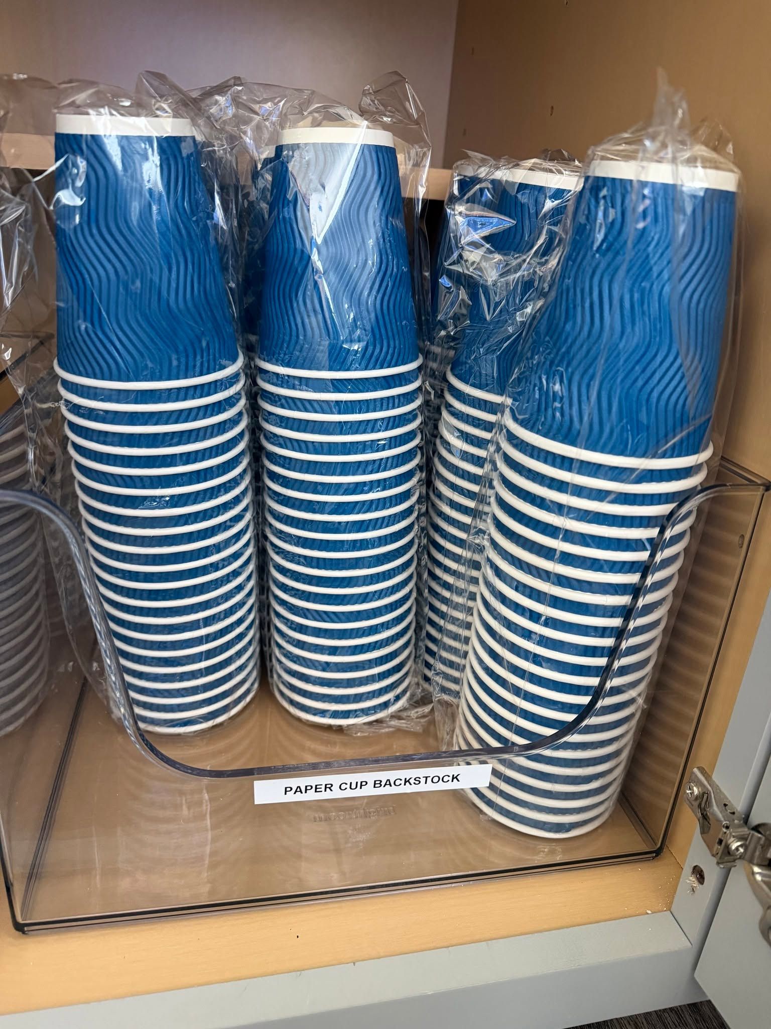 Stack of blue-and-white striped disposable cups in plastic wrap on a store shelf