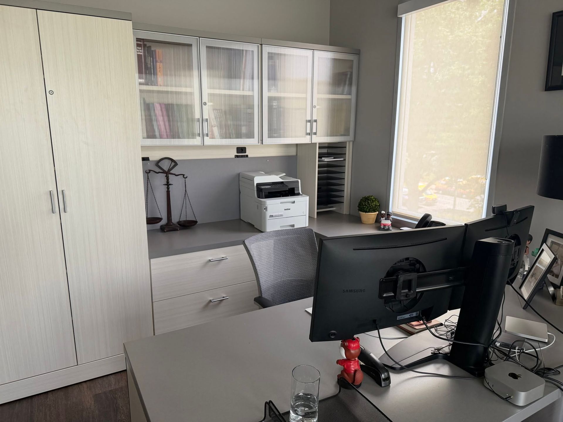 Home office with desk, computer monitors, cabinet shelves, and bright window light