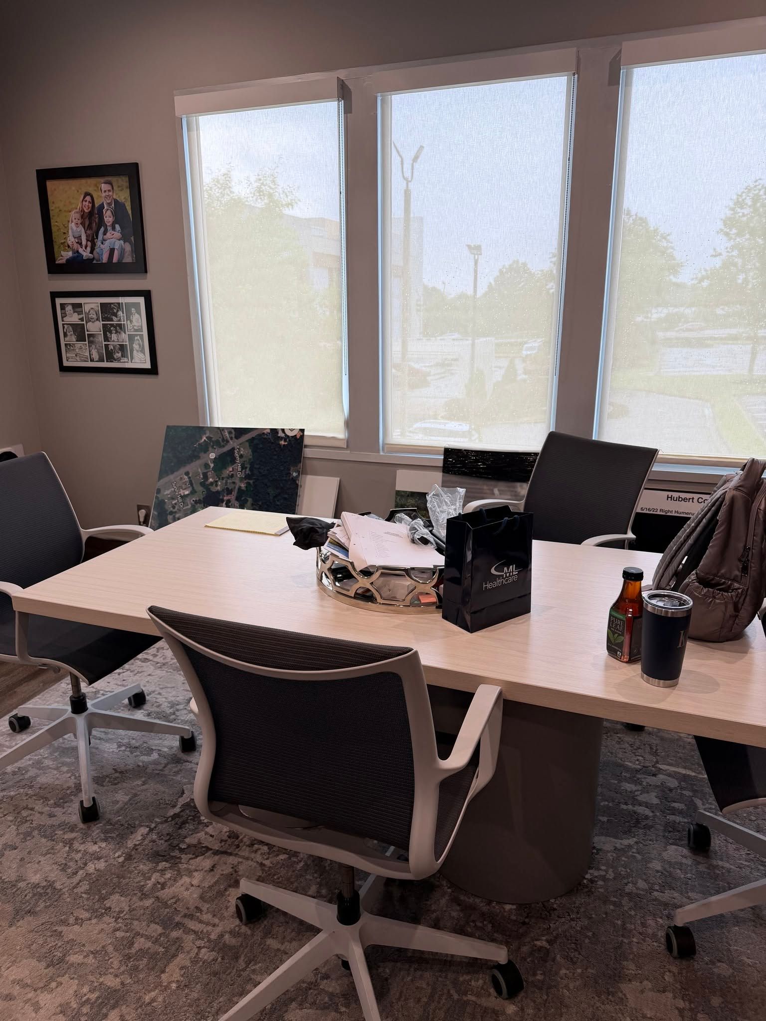 Conference room with a large table, black office chairs, and bright windows with blinds.