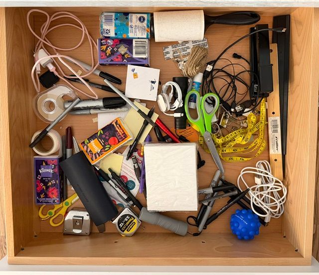 Drawer full of tangled cords, chargers, scissors, and small office supplies.