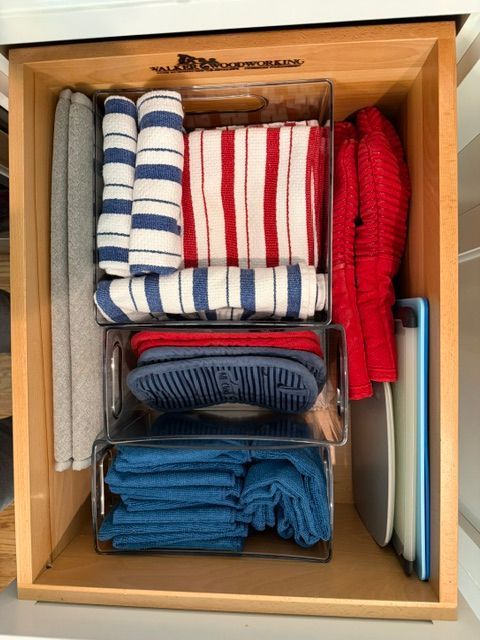 Bathroom drawer with folded striped towels and washcloths organized in clear bins
