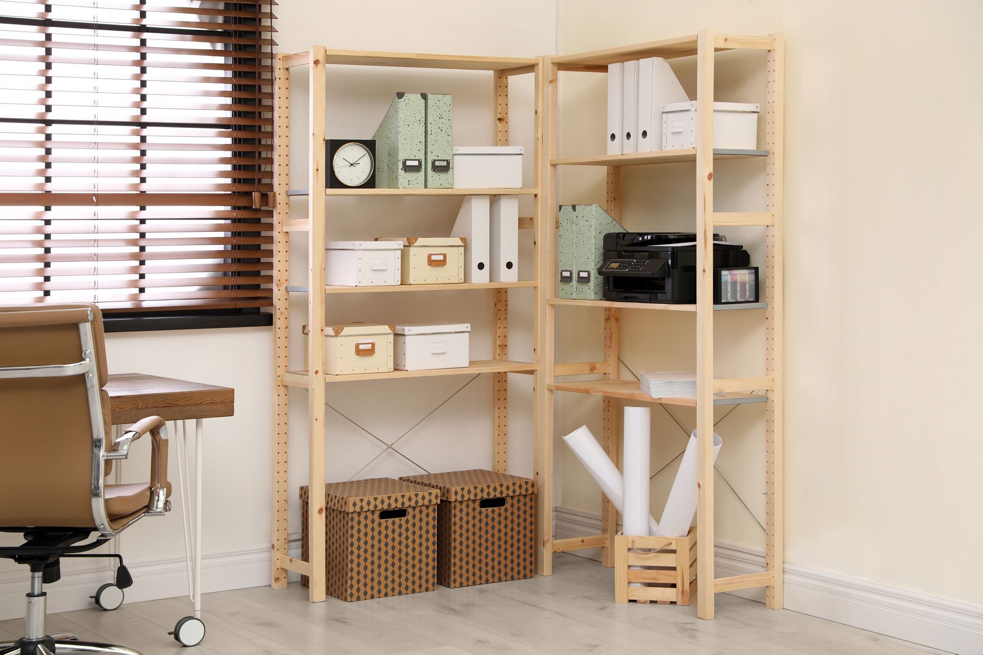 Home office shelving with boxes, baskets, and books beside a desk and chair
