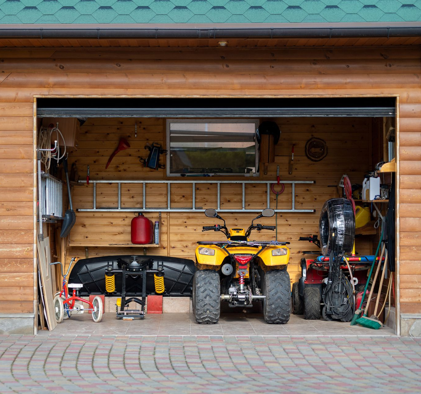 Garage with an ATV, black sled, and tools inside a wooden carport