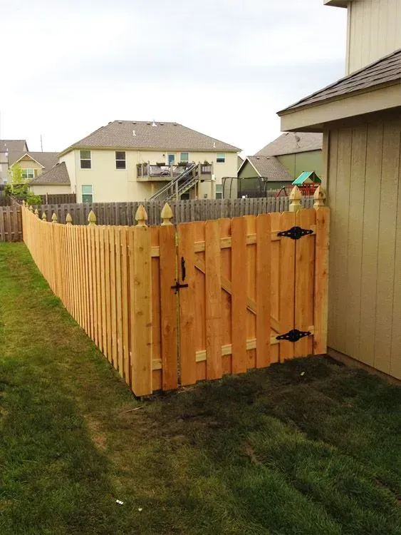 Wooden privacy fence with a gate in a suburban backyard beside a house