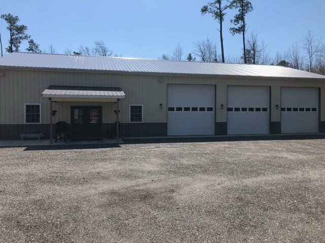A large building with a lot of garage doors is sitting on top of a dirt field.