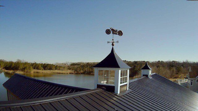 A weather vane on top of a building overlooking a lake