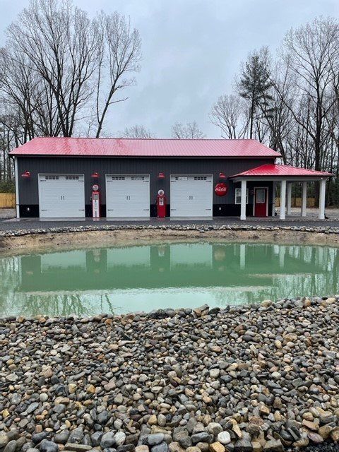 A garage with a red roof and a pond in front of it